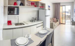 una cocina con armarios blancos y una mesa con dos platos. en FLATS ENSEADA Do SOL, en Jacumã