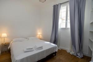 ein Schlafzimmer mit einem weißen Bett und einem Fenster in der Unterkunft Les Suites R Bonaparte - Appartements de standing au cœur de la vieille ville piétonne in Ajaccio