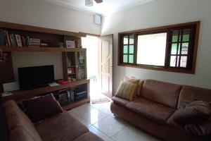 uma sala de estar com um sofá e uma televisão em Casa espaçosa à 100 m do mar em Mongaguá