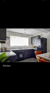 uma cozinha com armários pretos, uma mesa e uma janela em Spacious 3 bedroom house in nottingham em Nottingham