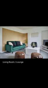 sala de estar con sofá verde y 2 reposapiés en Spacious 3 bedroom house in nottingham, en Nottingham