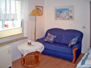 ein Wohnzimmer mit einem blauen Sofa und einem Tisch in der Unterkunft Ferienwohnung Haus Möwe in Freest