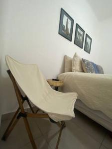 una sedia bianca seduta accanto a un letto di Linda Habitación en el Centro a Querétaro