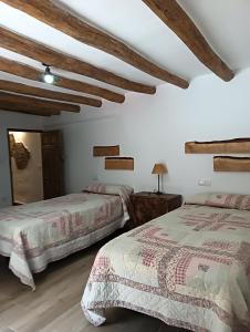 zwei Betten in einem Zimmer mit Holzdecken in der Unterkunft Vivienda Rural El Peñón de Los Primillas in La Iruela