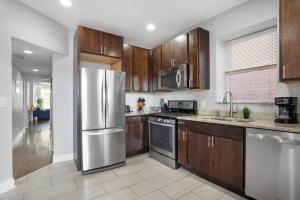 a kitchen with wooden cabinets and a stainless steel refrigerator at Game Day Getaway - 3BR in Vibrant Wrigleyville in Chicago