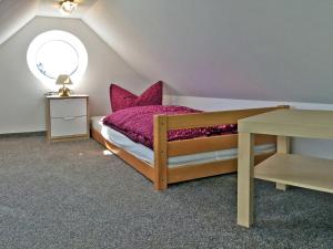 Schlafzimmer mit einem Bett mit rosa Kissen und einem Tisch in der Unterkunft Ferienwohnung Le Papillon in Kröslin