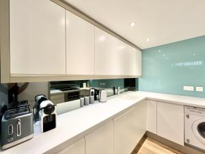 cocina con armarios blancos, lavadora y secadora en VIP SERVICED APARTMENTS LONDON ExCELLENT LOCATION GREAT PRICE, en Londres
