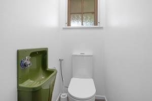 a white bathroom with a toilet and a window at Maratoa - Takaka Holiday Home in Takaka