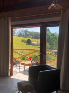 uma sala de estar com vista para um campo através de uma janela em Casa Serrinha - Lindo e Espaçoso Chalé em Bueno Brandão