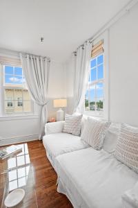 a white living room with a white couch and two windows at ORCHID SUITES - Historic Palm Beach Hotel Condominium in Palm Beach
