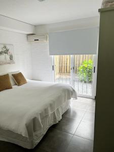 a bedroom with a white bed and a large window at IPB la Juanita Oeste in José Ignacio