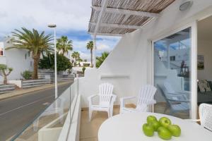 een balkon met witte stoelen en een tafel met fruit erop bij Casa Anzuelo, Puerto del Carmen in Puerto del Carmen