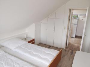 een witte slaapkamer met een bed en een koelkast bij Ferienwohnung Schimmer 27 in Braunlage