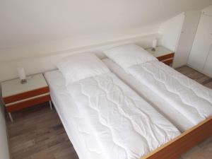 een groot wit bed in een kamer met 2 tafels bij Ferienwohnung Schimmer 27 in Braunlage