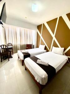 una habitación de hotel con 2 camas y una silla en Hotel Plaza Teatro, en Chiclayo