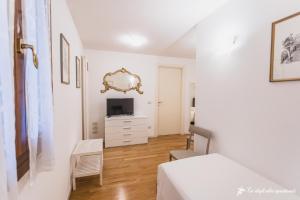 a white bedroom with a bed and a tv at Ca' degli Ulivi in Creazzo