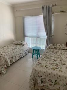 a bedroom with two beds and a blue table at Pe na areia frente mar in Balneário Camboriú