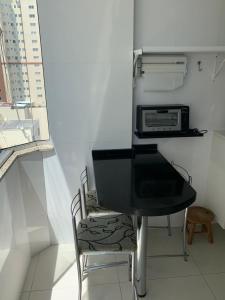 a small kitchen with a black table and a microwave at Pe na areia frente mar in Balneário Camboriú