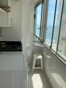 a white bathroom with a sink and a window at Pe na areia frente mar in Balneário Camboriú +9 photos