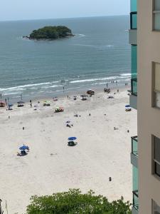 a beach with people and umbrellas and the ocean at Pe na areia frente mar in Balneário Camboriú