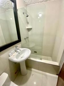 y baño blanco con lavabo y ducha. en Hotel Plaza Teatro, en Chiclayo