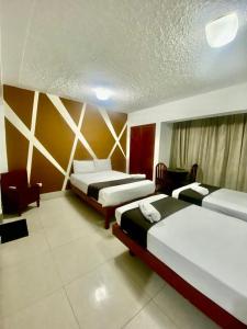 um quarto de hotel com duas camas e uma cadeira em Hotel Plaza Teatro em Chiclayo