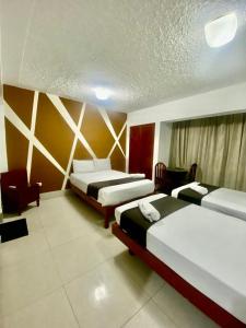 una habitación de hotel con 2 camas y una silla en Hotel Plaza Teatro, en Chiclayo