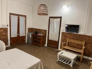 a bedroom with a bed and a chair and a tv at La Blanquita de Areco in San Antonio de Areco