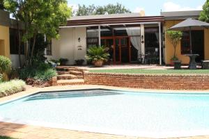a swimming pool in front of a house at Jubilee Lodge Guest House in Johannesburg