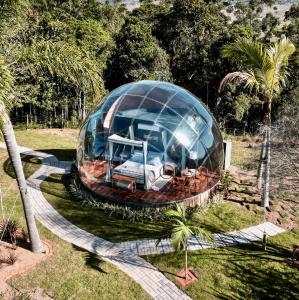 a glass dome in a field with a house at Casa bolha in Imaruí