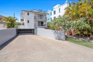 an empty driveway in front of a white building at Bilinga Beach House in Gold Coast