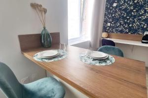 una mesa de madera con dos platos y un jarrón en ella en Studio entièrement rénové proche gare, en Cambrai