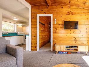 a living room with a wooden wall with a tv at Kaka Retreat - Taupo Holiday Home in Taupo