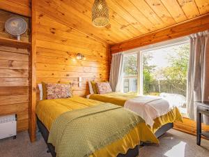 two beds in a log cabin with a window at Kaka Retreat - Taupo Holiday Home in Taupo