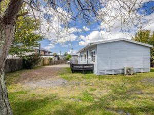 a small white shed in a yard with a tree at Kaka Retreat - Taupo Holiday Home in Taupo