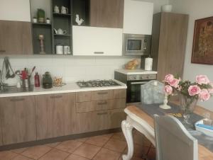 una cocina con armarios de madera y una mesa con flores rosas en Semplicemente a casa, en Roma