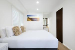 バイロンベイにあるByron Bay Beachfront Holiday Apartments Courtyard 1の白いベッドルーム(大きな白いベッド1台付)