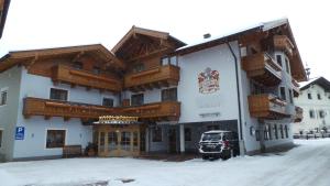 un gran edificio blanco con balcones de madera en la nieve en Hotel Hörlgut en Maria Alm am Steinernen Meer