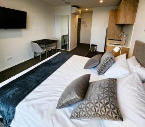 a bedroom with a large white bed with pillows at The Residences Ellerslie in Auckland