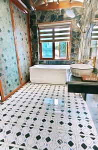 a bathroom with a tub and a sink and a tiled floor at Hang Mua Eco Garden in Xuân Sơn