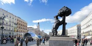 a statue in a city with people walking around at Remanso de luz y silencio en plena Puerta del Sol in Madrid