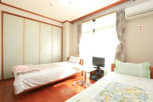 a bedroom with two beds and a desk and a window at Minshuku Satomachi in Yakushima