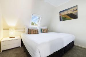 バイロンベイにあるByron Bay Beachfront Holiday Apartments Penthouse 10の白いベッドと窓のある白い寝室