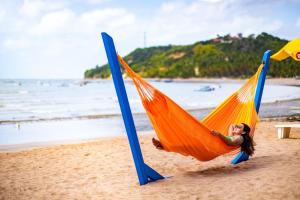 a woman laying in a hammock on a beach at Sol do Caribe Suítes in Maragogi +15 photos