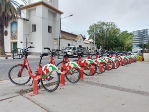 een rij rode en groene fietsen geparkeerd op een stoep bij Departamento Carrodilla Luján in Ciudad Lujan de Cuyo