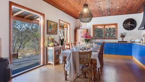 comedor con mesa y sillas y cocina en Cedar Cottage, en Canyonleigh