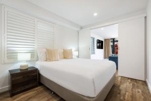 バイロンベイにあるByron Bay Beachfront Holiday Apartments Courtyard 6の大きなベッドと窓のある白い寝室