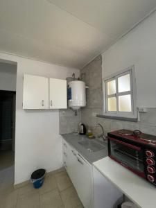 eine Küche mit weißen Schränken, einem Waschbecken und einem Fenster in der Unterkunft Bungalows palmar in Chajarí