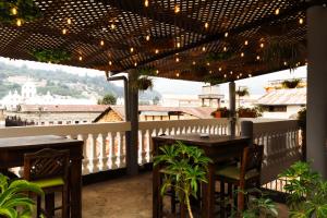 a patio with tables and chairs on a balcony with lights at Lar Antiqua Hotel in Quetzaltenango
