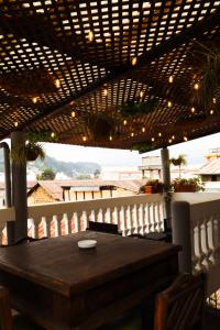 einen Holztisch auf einem Balkon mit einer Pergola in der Unterkunft Lar Antiqua Hotel in Quetzaltenango